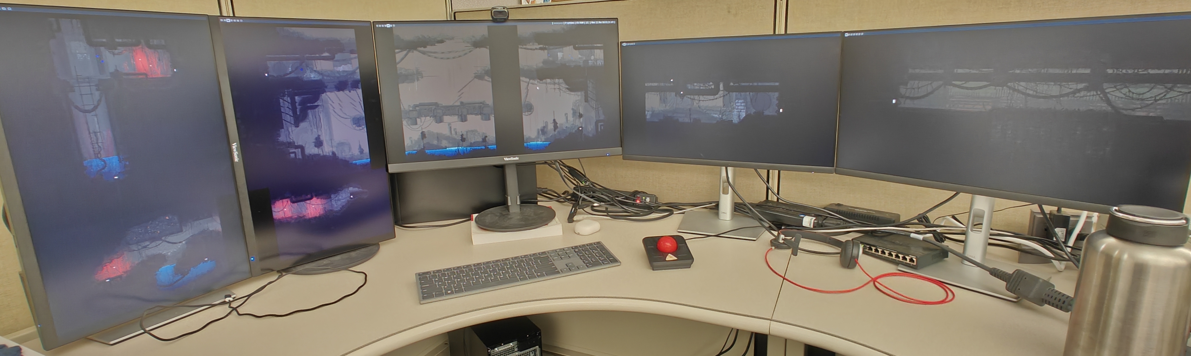 A picture of a computer setup. There are multiple monitors each only displaying a wallpaper, which is stretched across all of the monitors.